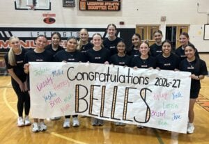 A group photo of fourteen members of the Liberty Belles dance team holding a celebratory banner for the 2026-2027 season, signed with the names of all team members.